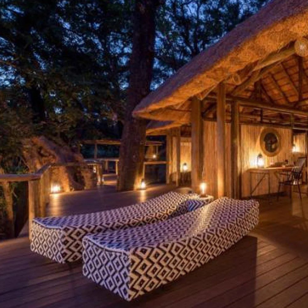 Des transats à motifs reposent sur la terrasse sous le chaume à Chamilandu Bushcamp