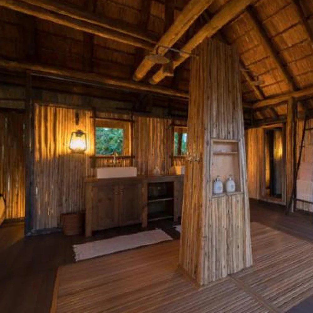 Salle de bains ouverte avec un meuble-vasque en bois et un bassin en pierre à Chamilandu Bushcamp
