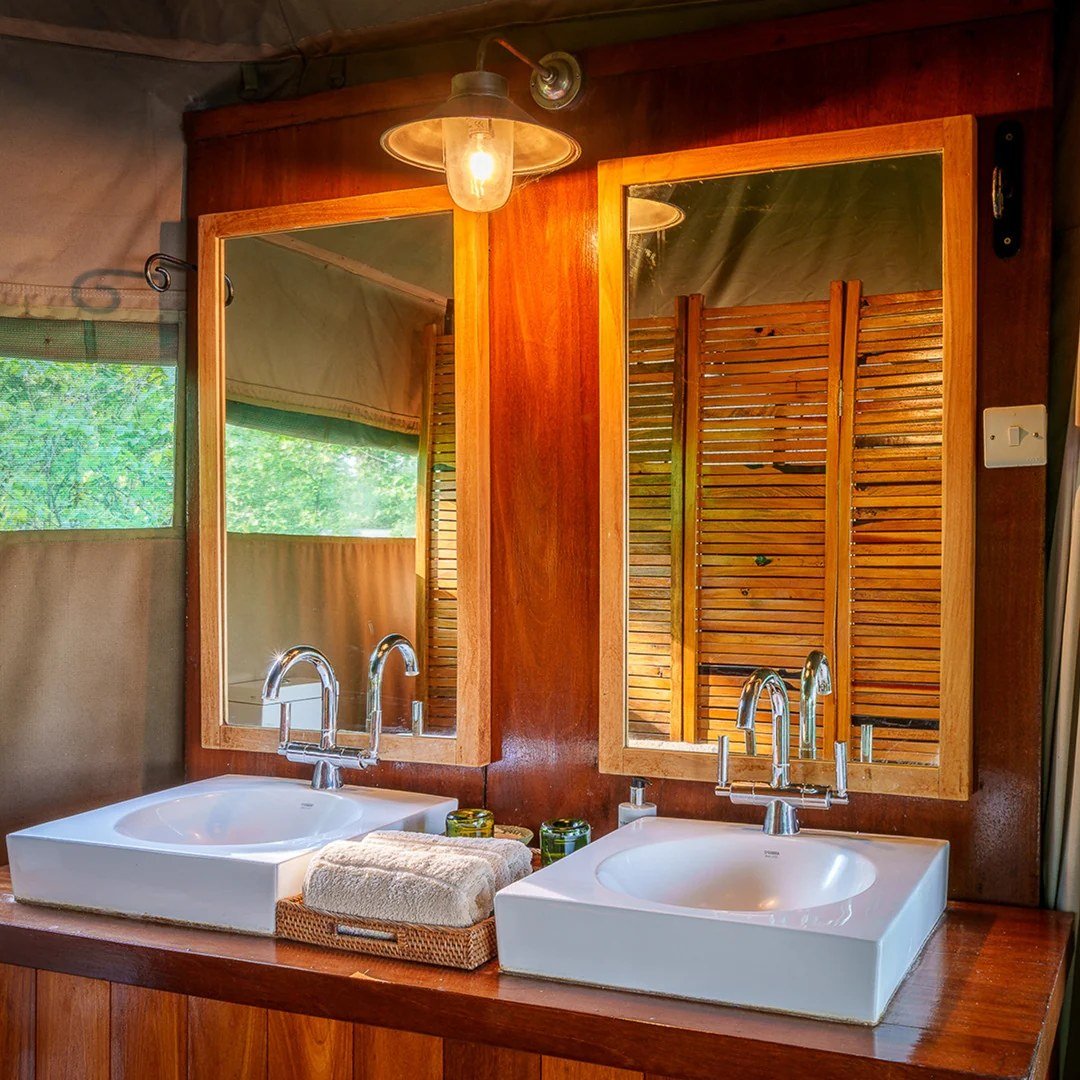 Double vasque avec miroirs à cadre bois et robinets en laiton à Chindeni Bushcamp