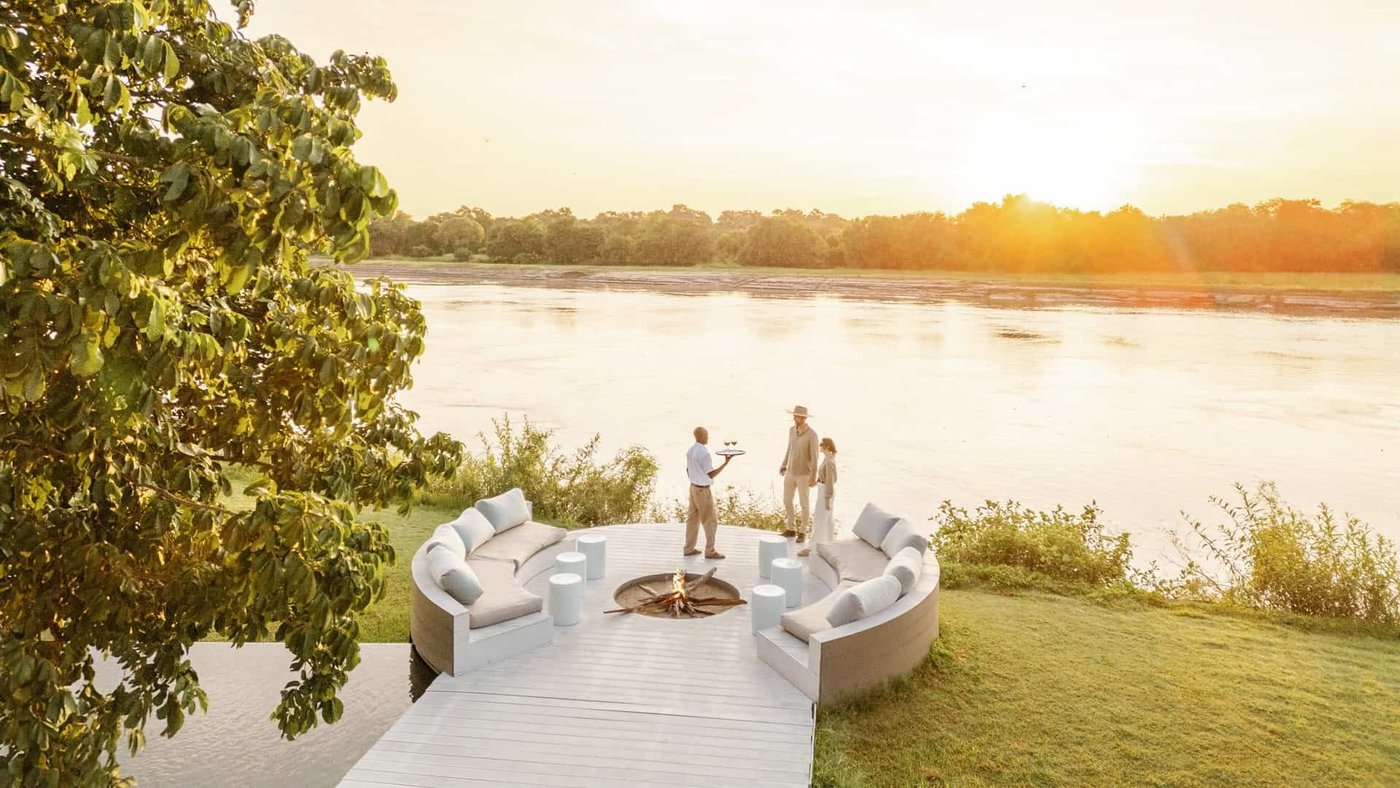 Sièges de salon courbes sur la pelouse au-dessus de la rivière Luangwa au crépuscule, Chinzombo, South Luangwa