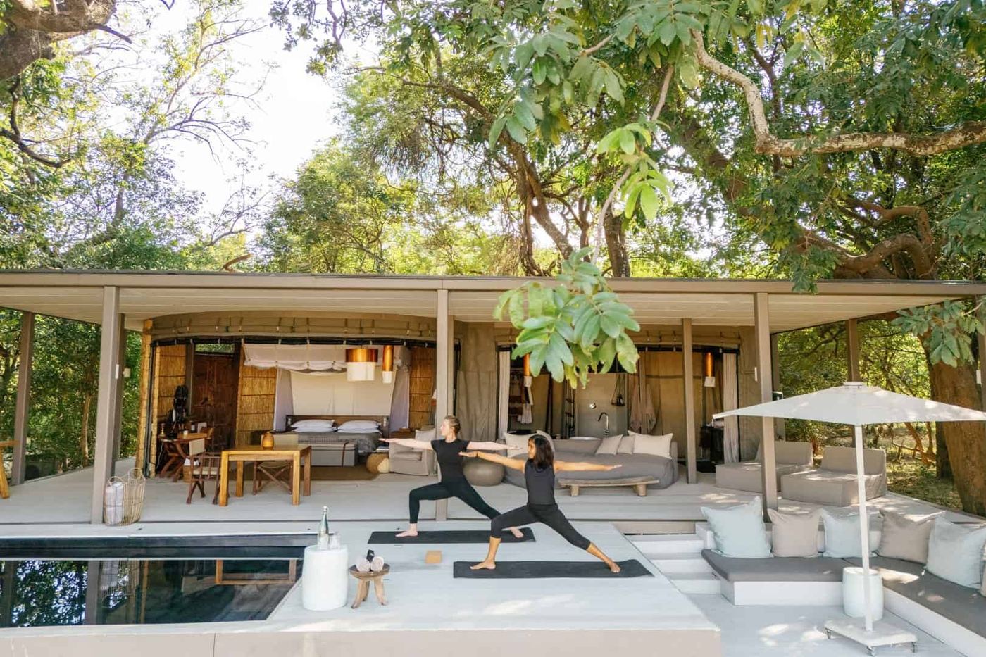 Terrasse de piscine avec chaises longues et tapis de yoga sous les arbres à Chinzombo