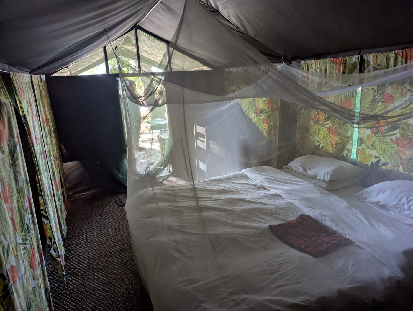Chambre de tente avec une moustiquaire et un couvre-lit coloré à Croc Valley Camp