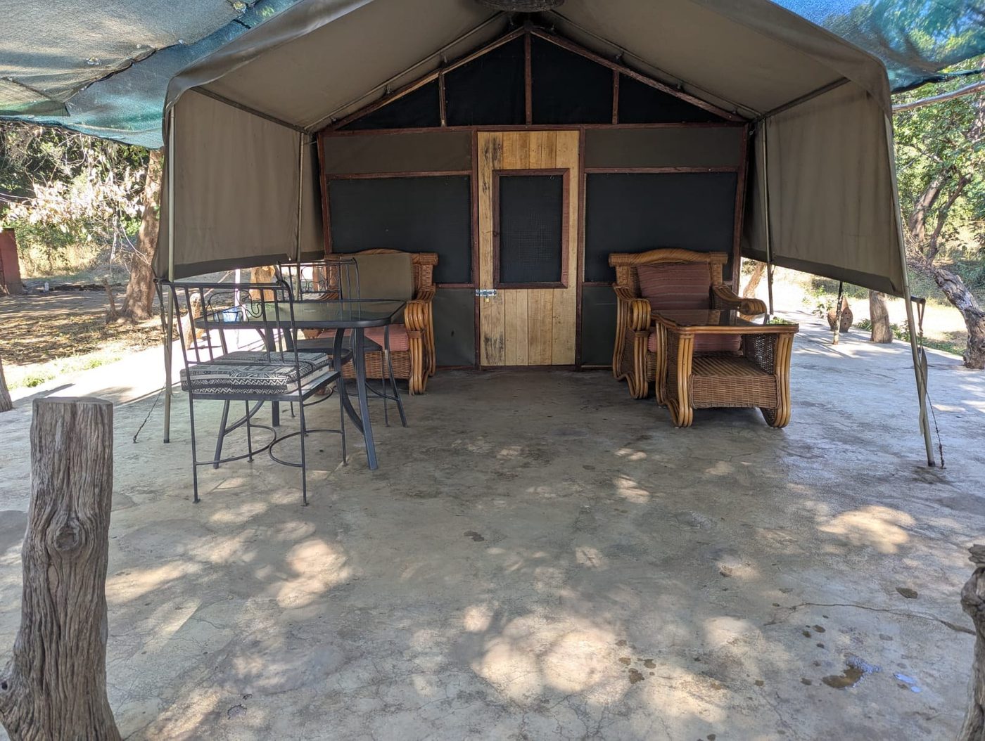 Chalet de tente avec places assises extérieures sous un cadre couvert de chaume à Croc Valley Camp