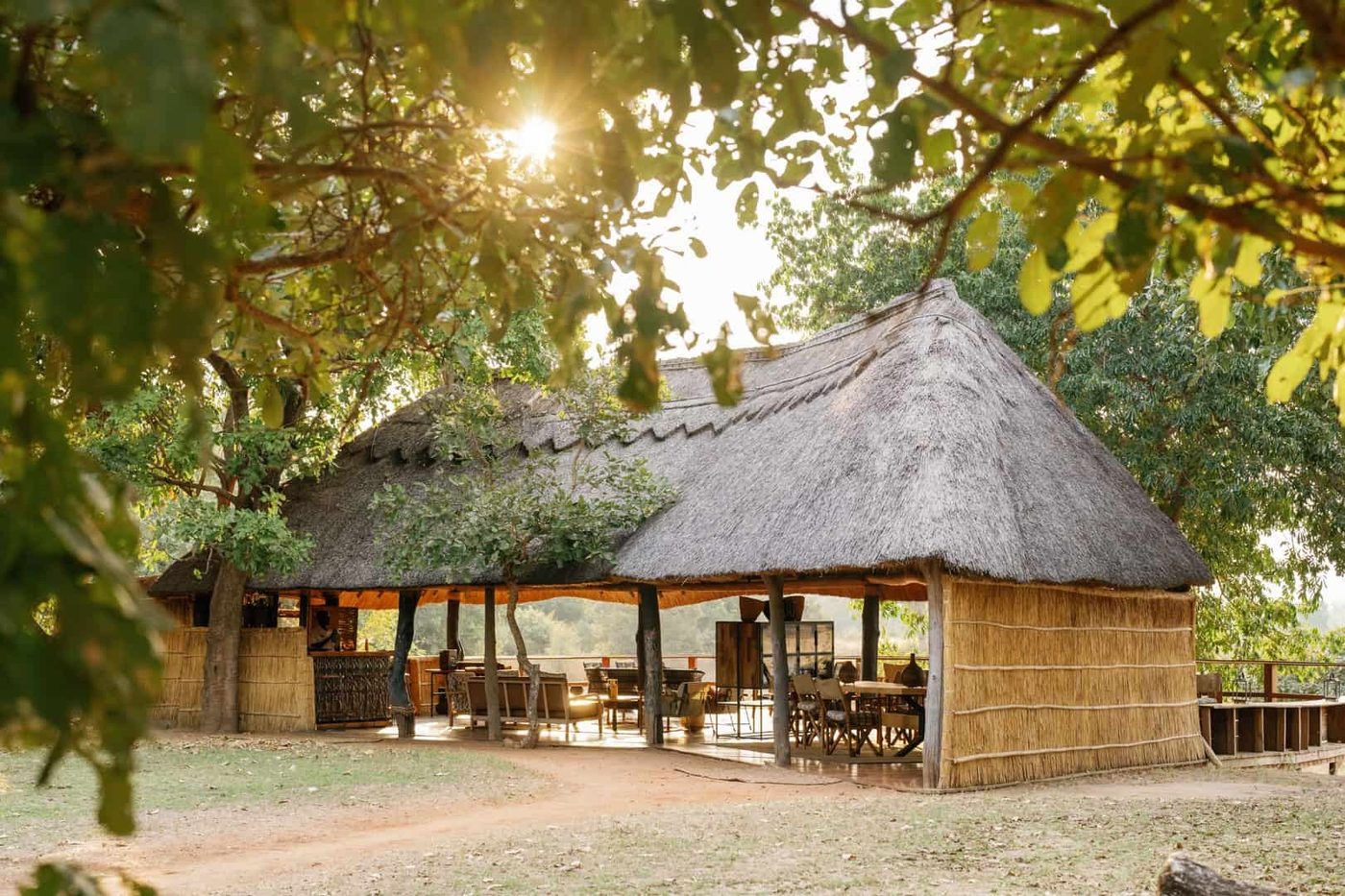 Bâtiment de loge principale en chaume éclairé par le soleil du matin à travers les arbres, Kakuli, South Luangwa