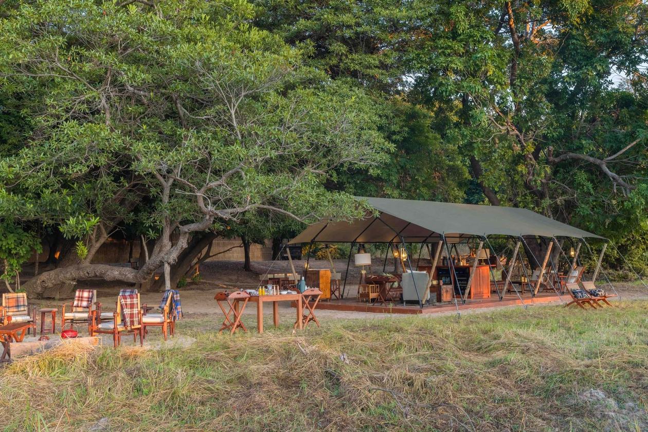 Lounge et terrasse à manger sous une tente commune, installées parmi les arbres à Luwi, South Luangwa