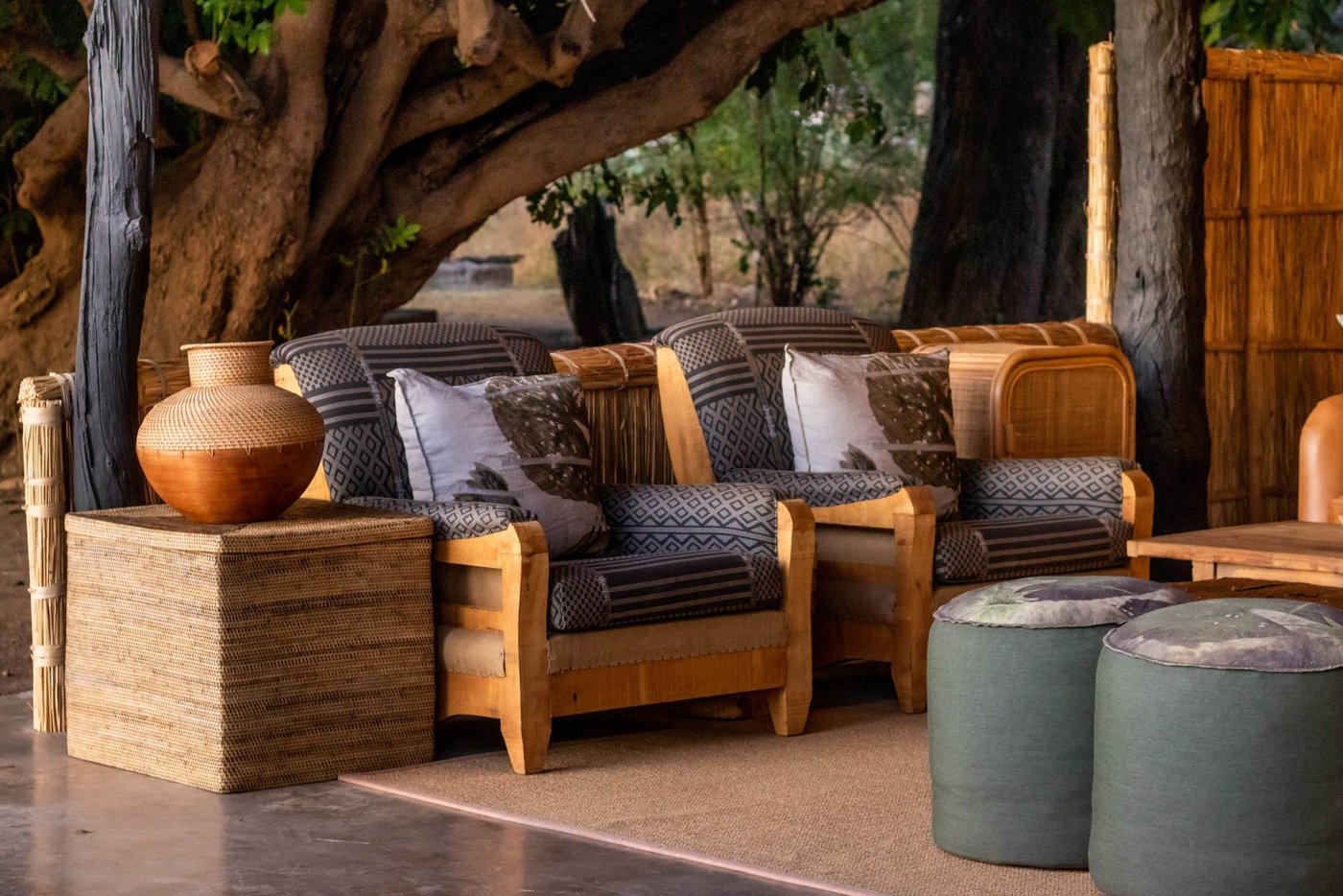 Un fauteuil tressé niché sous un grand arbre chez Mchenja