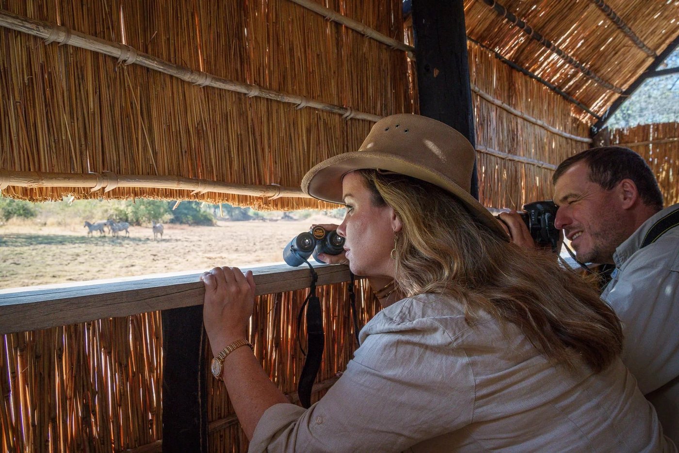 Des clients observent les oiseaux avec des jumelles depuis la terrasse de Nsefu Camp