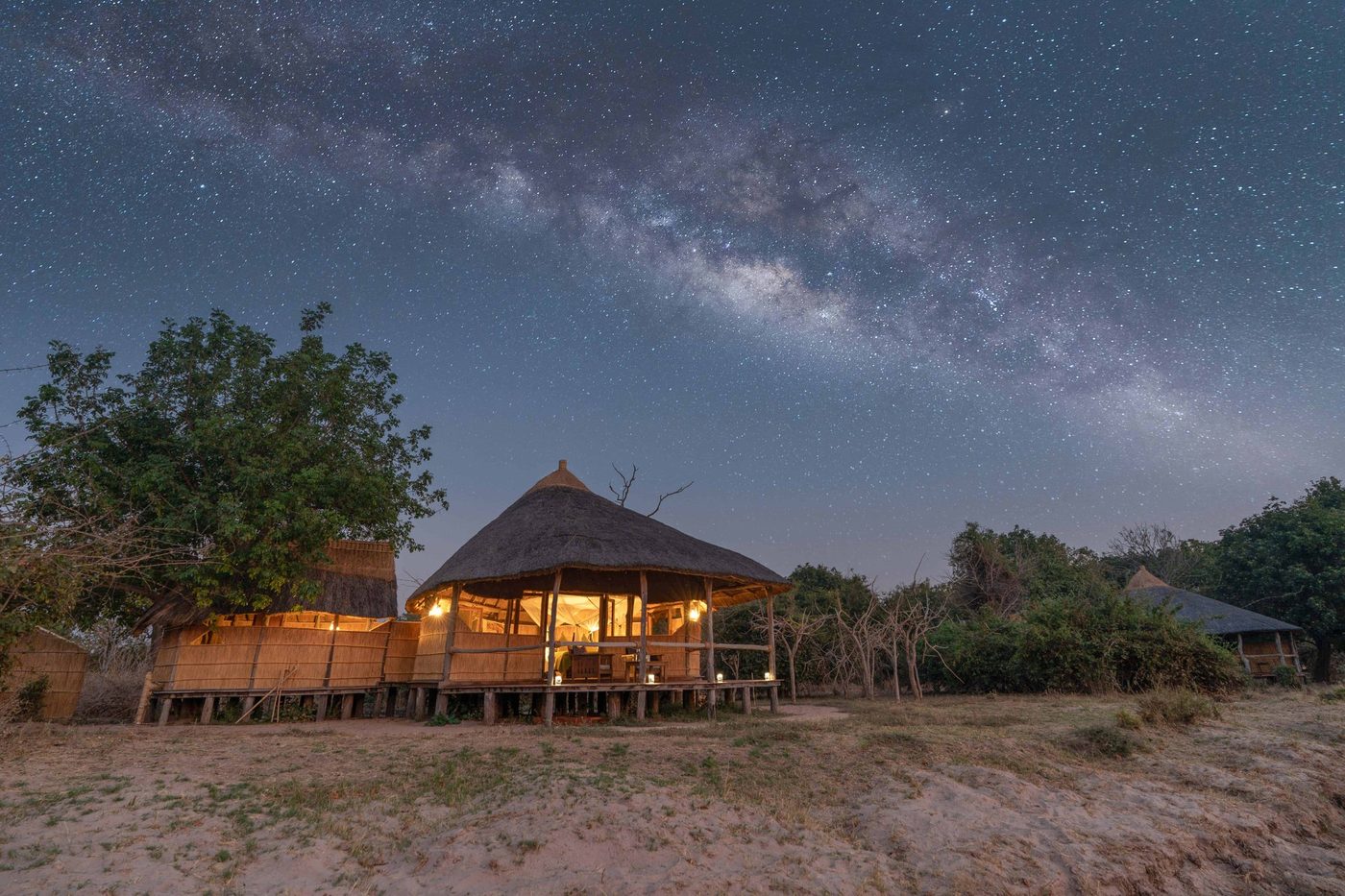 Camp en chaume brillant sous la Voie lactée la nuit, Nsolo, South Luangwa