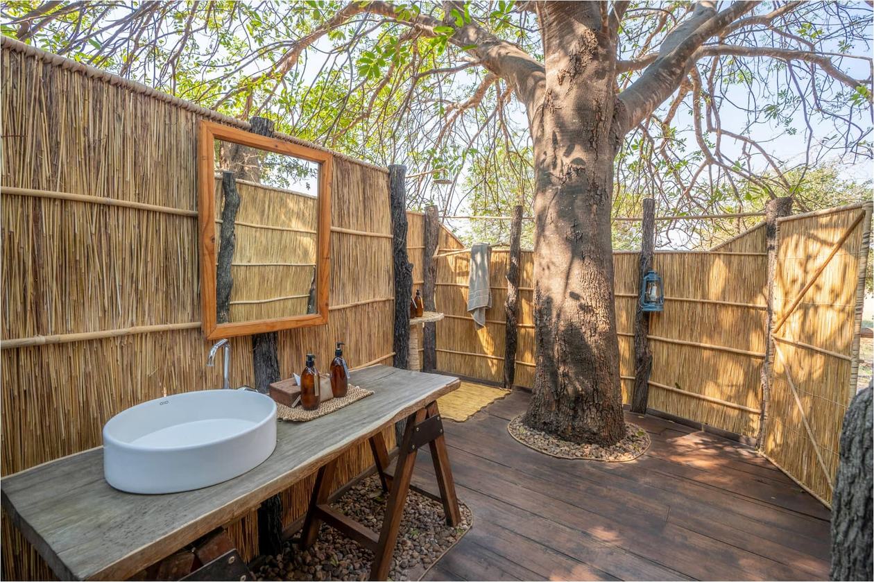 Lavabo de pierre en plein air et miroir sous un baobab à Nsolo