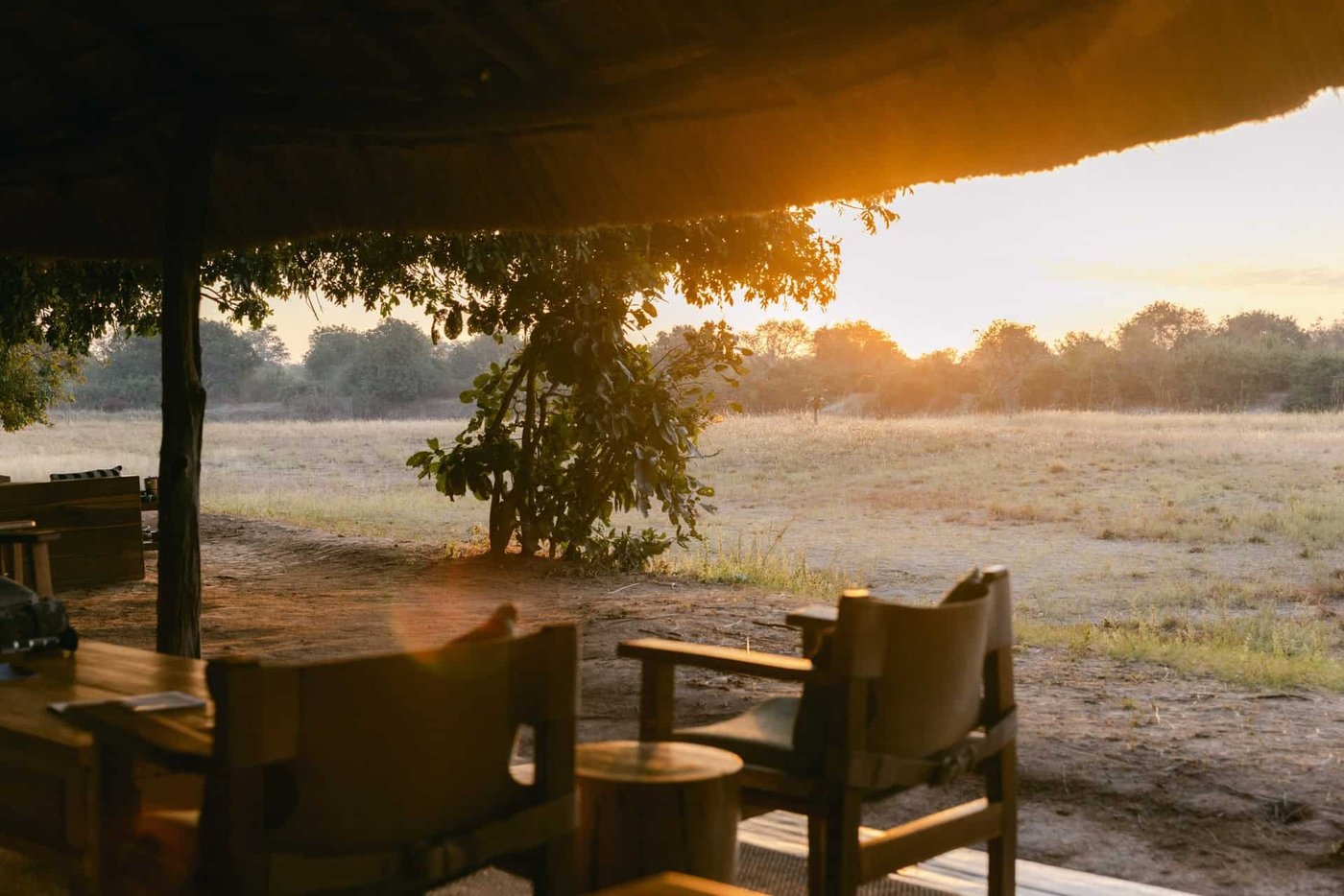 Terrasse couverte avec des chaises de safari dominant la plaine au coucher du soleil, Nsolo
