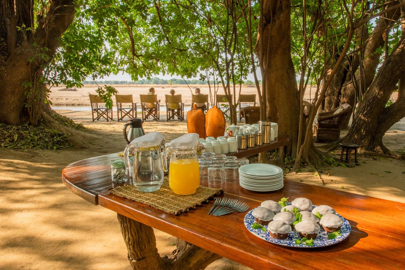 Les viennoiseries et le jus du petit-déjeuner sont disposés au-dessus du lit asséché de la rivière à Tafika Camp