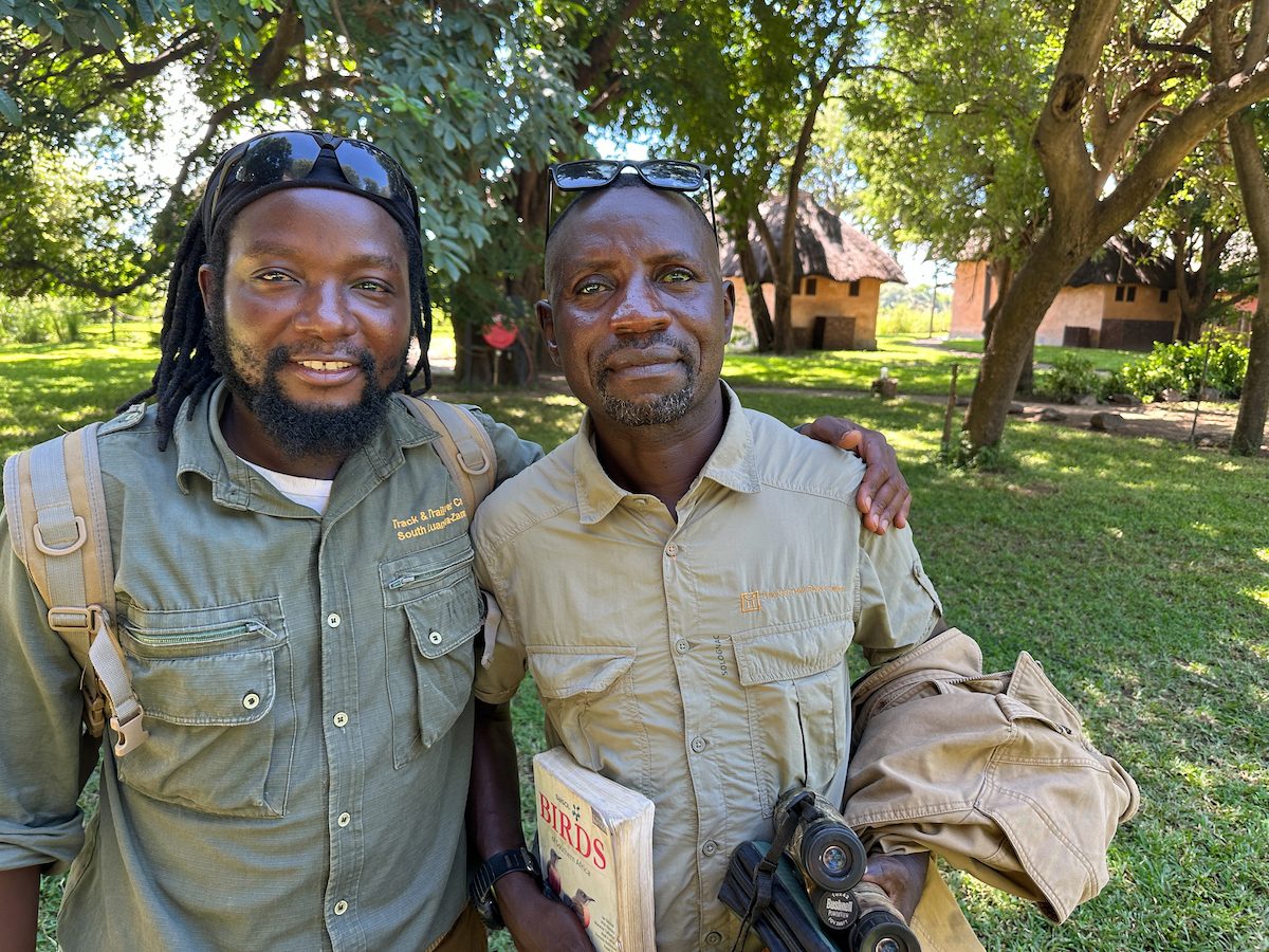 Guides Steve, left, and Vickson, right, in camp with a bird book and binoculars