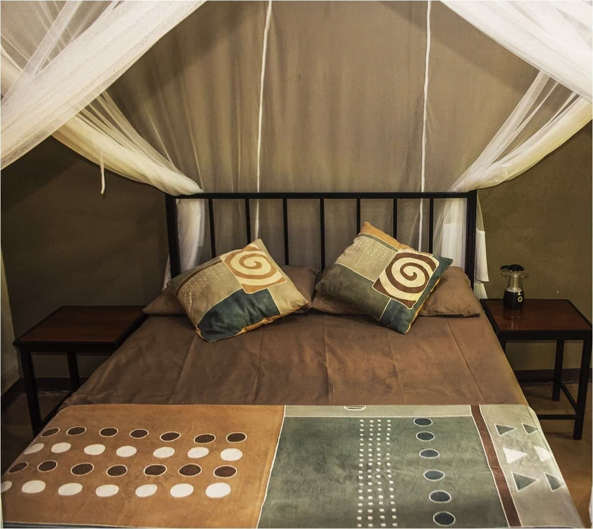 Chambre de tente avec une moustiquaire et un couvre-lit coloré à Wildlife Camp