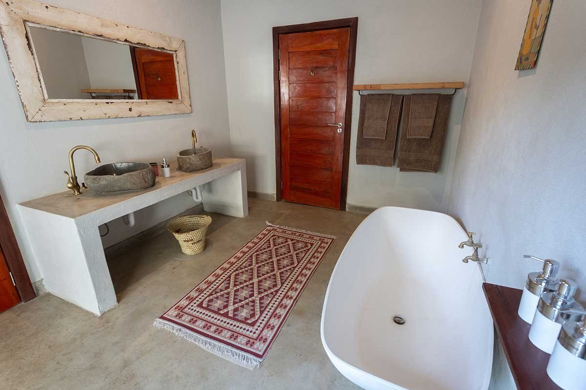 Baignoire indépendante et tapis à motifs dans une salle de bain en plein air à Zikomo Safari Camp