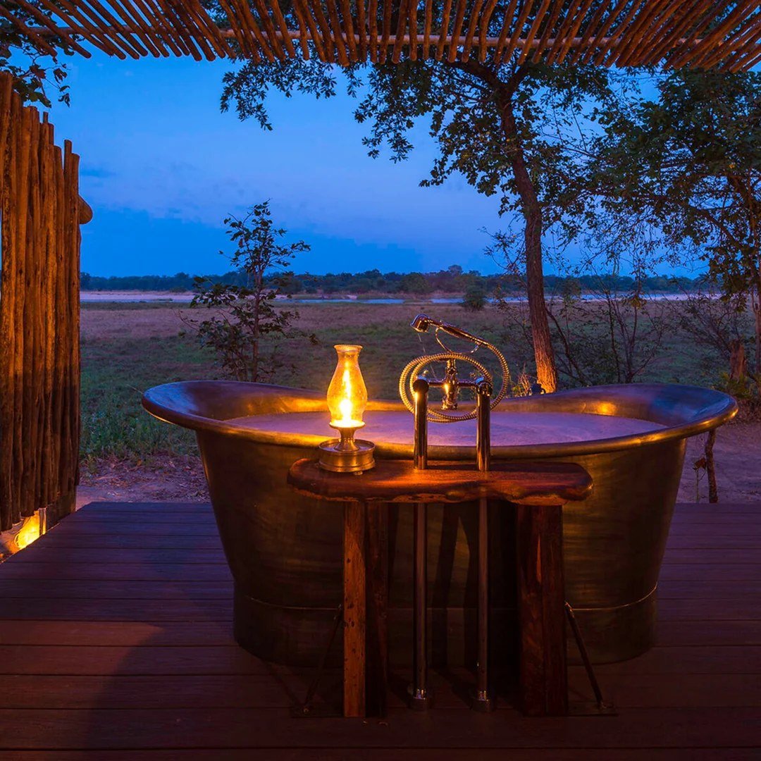 Une baignoire en cuivre fait face à la plaine ouverte au crépuscule, Zungulila Bushcamp